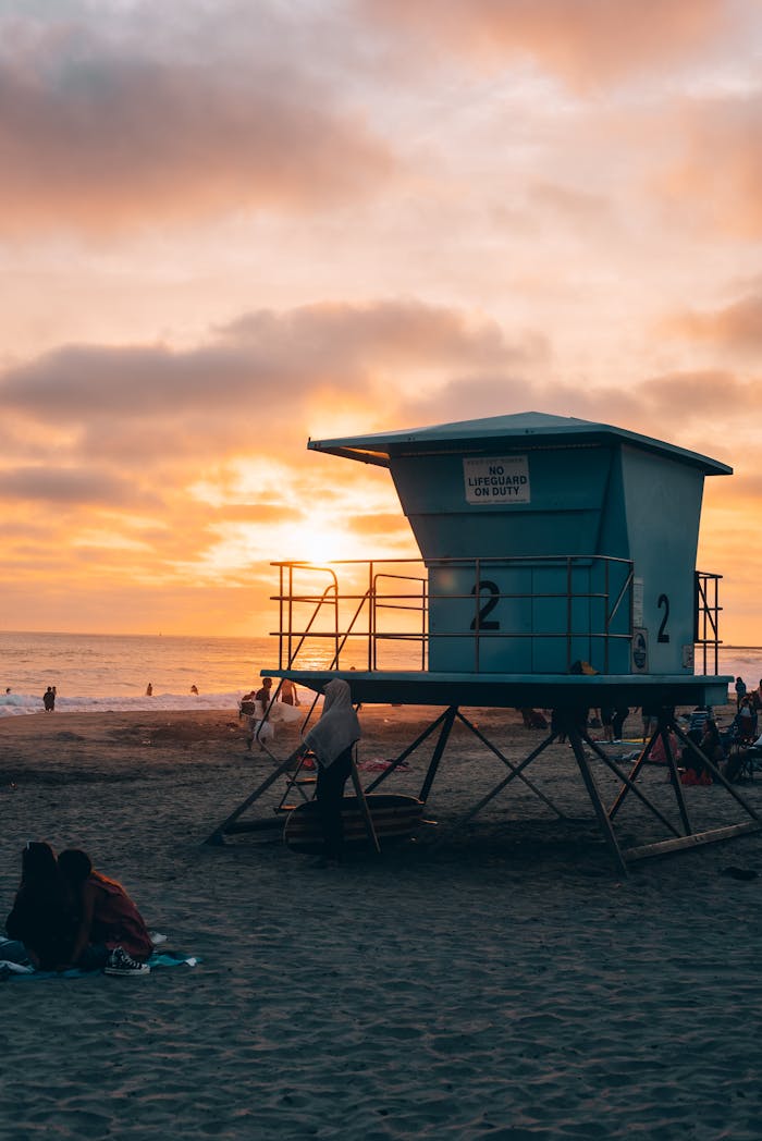 Beautiful sunset at a California beach with a lifeguard tower and people enjoying the view.